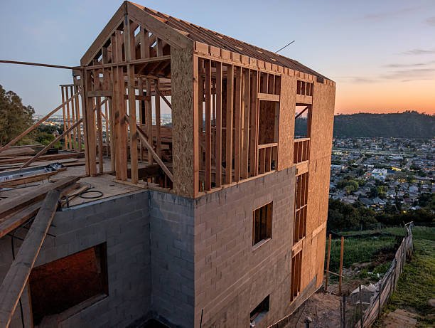 A house under construction with a sunset backdrop, showcasing the progress of ADU construction.