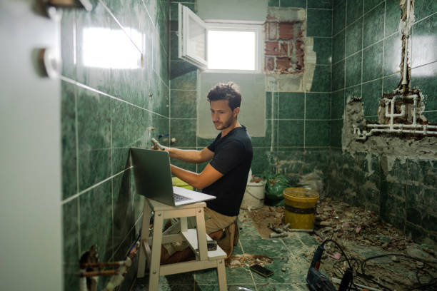 Two people shaking hands over a table, discussing a bathroom remodel project with a contractor.
