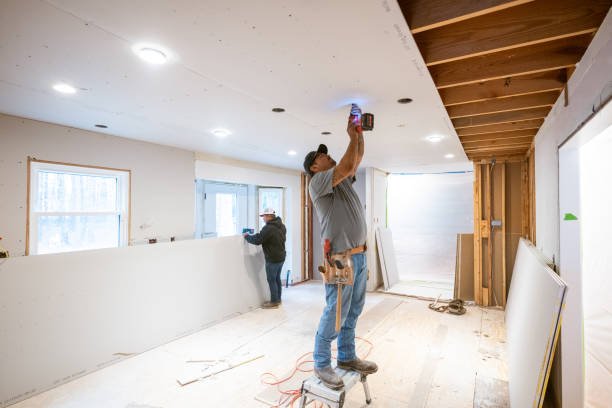 A man works on the ceiling of a home during a full renovation project.
