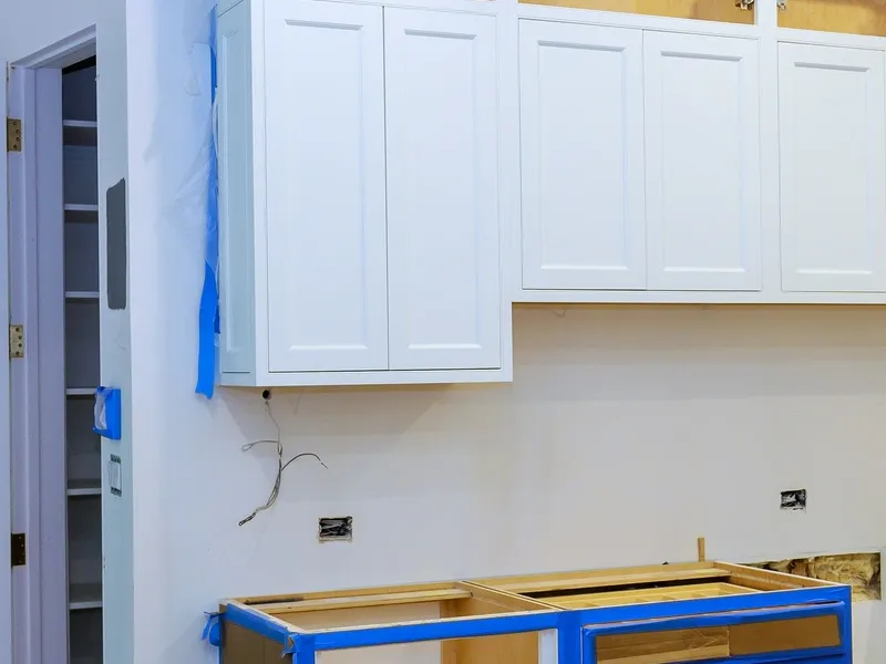 Garage conversion in progress with new white shaker cabinets and finished walls