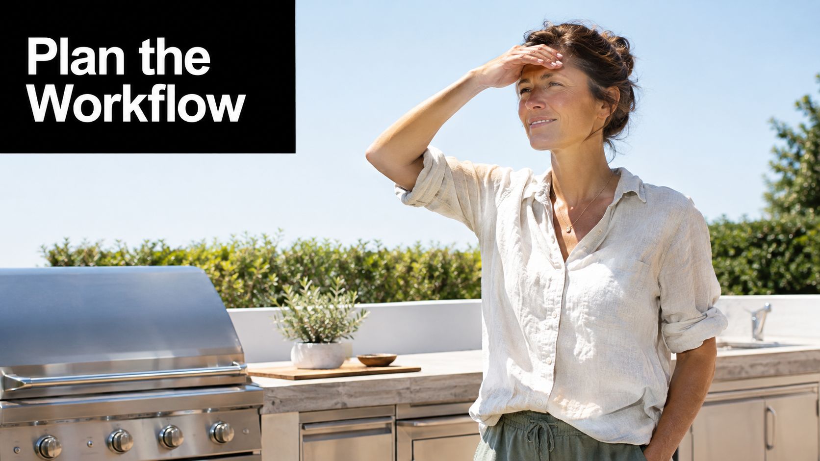 A woman stands in a bright outdoor kitchen space while shielding her eyes from the bright sun.